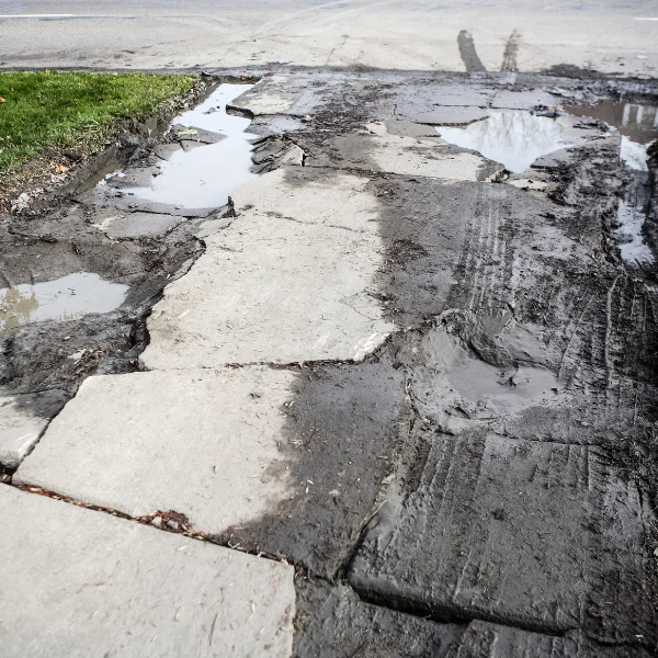 An image showing a cracked and uneven residential driveway.